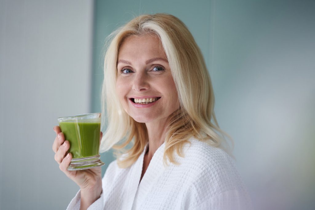 Woman holding glass of green juice